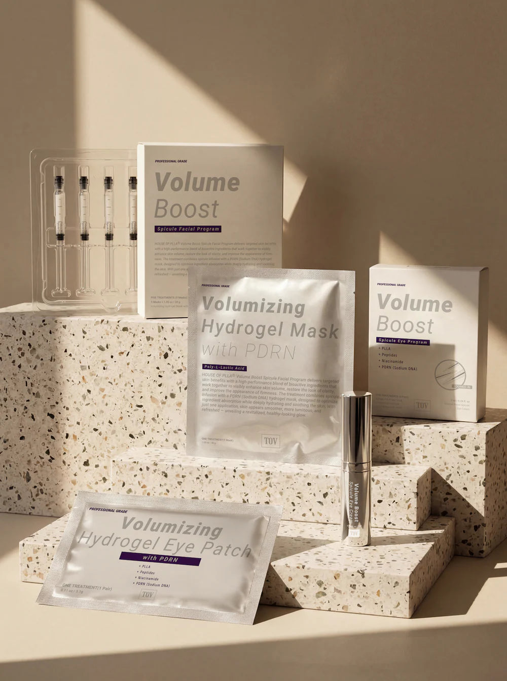 Volume Boost skincare products including a mask, eye patch, and syringe on a textured surface.